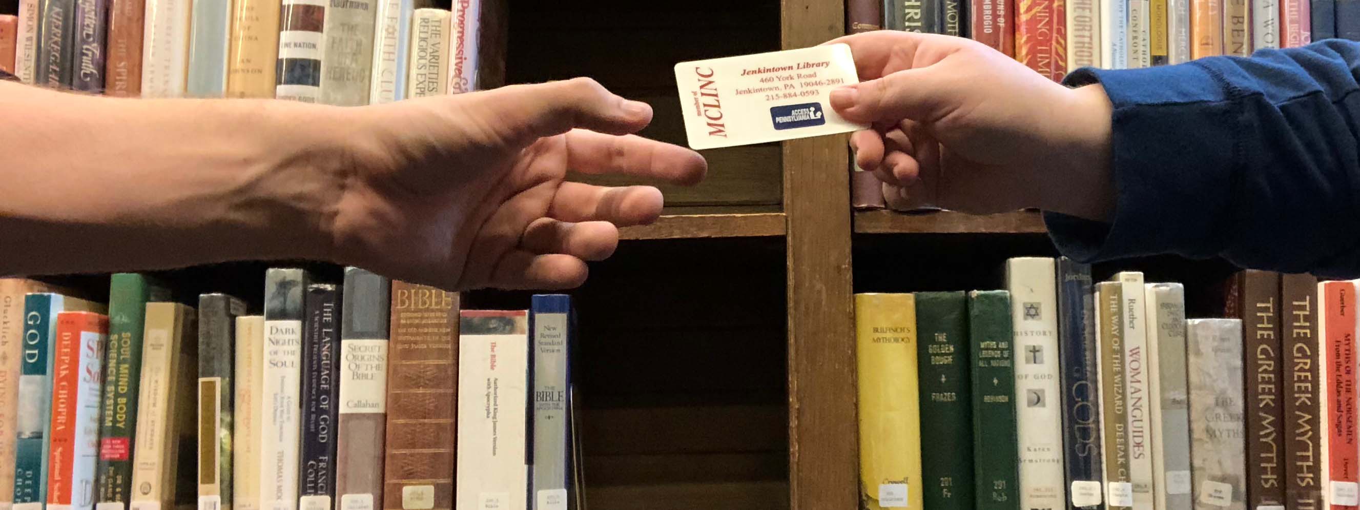 a hand reaching toward a library card being held out 